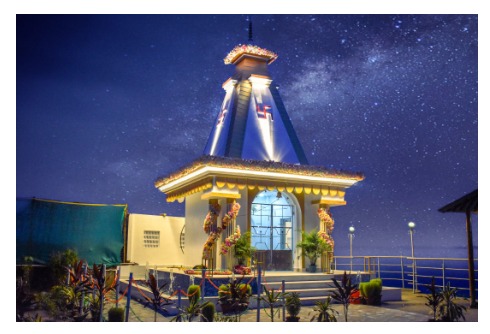 Illuminated riverside temple at night with starlit sky