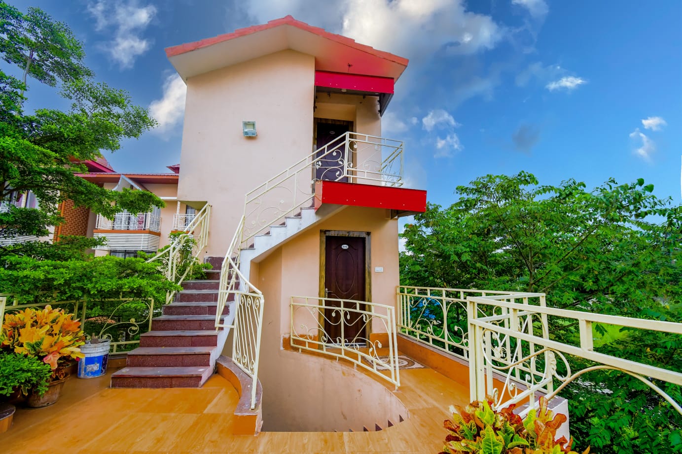 Duplex cottage exterior with staircase and lush greenery